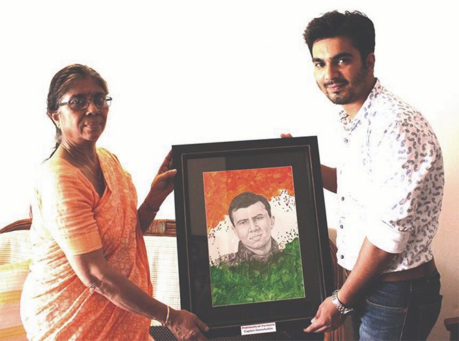 Mrs Hema Aziz receives a portrait of her son from artist  Hutansh Verma who paints pictures of martyrs and gifts them to their families.