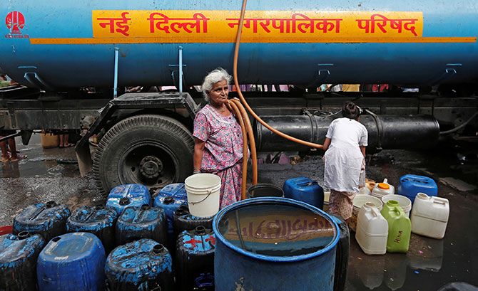 A woman stands after filling her containers with drinking water from a municipal tanker in New Delhi. Photograph: Adnan Abidi/Reuters. 