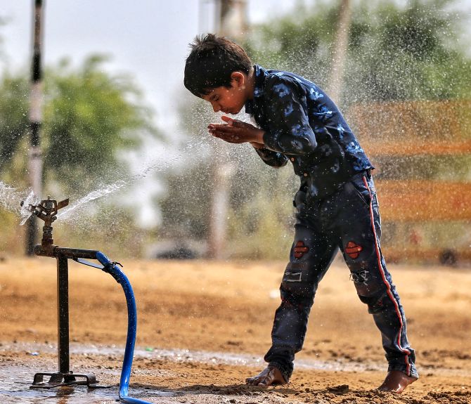 A young boy stands next to a leaking water source in Churu. Photograph: PTI Photo