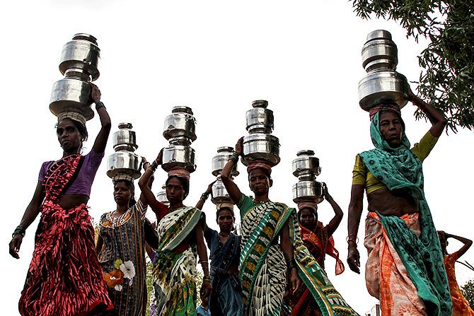 Women carry pitchers filled with water. Photograph: Prashant Waydande/Reuters