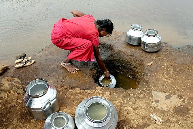 A woman fetches water from an opening made to filter water next to a polluted lake in Maharashtra's Thane district. Photograph: Prashant Waydande/Reuters