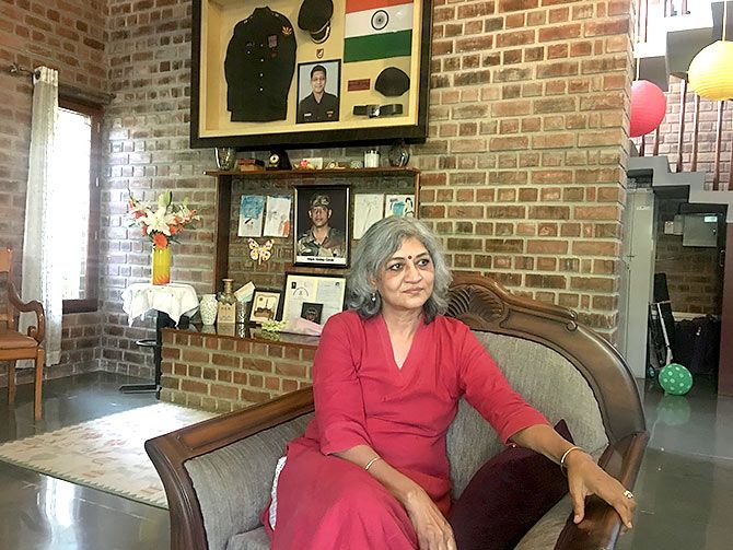 Meghna Girish surrounded by photographs, uniforms, medals that belonged to her soldier-son.