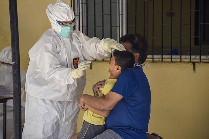 A doctor is about to use a swab on a child in Borivali, north west Mumbai, April 7, 2020.