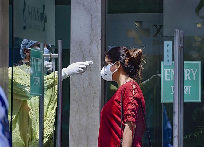 A paramedic checks the temperature of a patient at a hospital in New Delhi, April 27, 2020. Photograph: Ravi Choudhary/PTI Photo