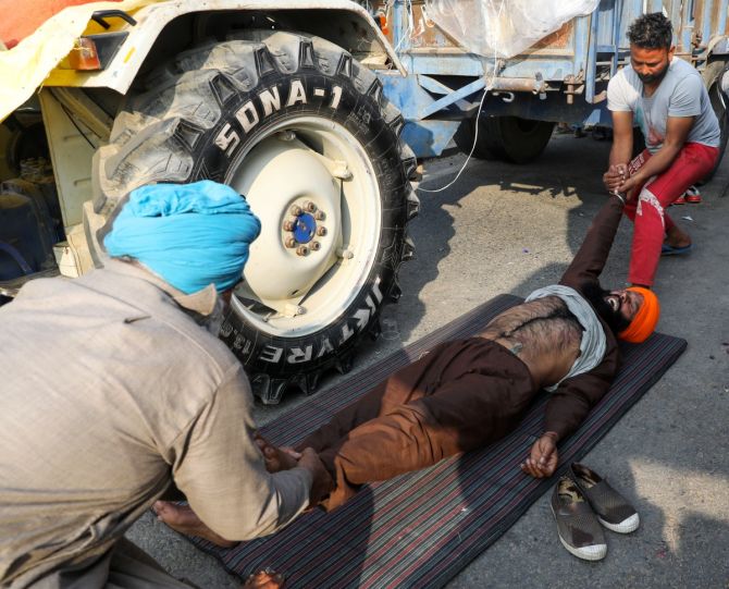 A farmer reacts as men pull his hand and leg at the site of a protest