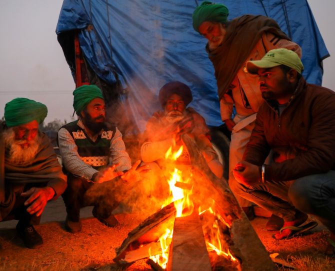 Farmers sit around a bonfire at the site of a protest