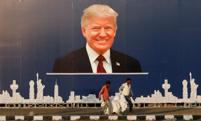 Workers walk past a hoarding of United States President Donald J Trump ahead of his visit to Ahmedabad, February 22, 2020. Photograph: Anushree Fadnavis/Reuters