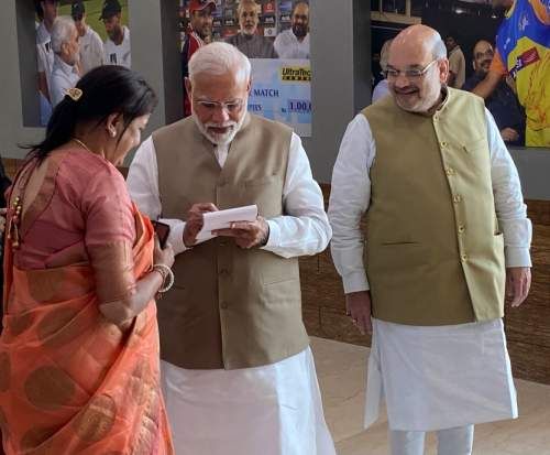 Prime Minister Narendra Damodardas Modi scribbles a message for Sonalben Shah as her husband wearing a big smile watches at the Motera stadium, February 24, 2020.
