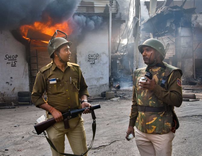 Policemen outside a burning shop in the Gokulpuri area of north east Delhi, February 26, 2020. Photograph: PTI Photo