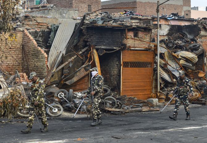 Sashastra Seema Bal personnel walk past burnt and damaged shops at Gokalpuri market in north east Delhi. Photograph: Kamal Kishore/PTI Photo