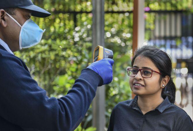 Personnel deploy a thermal screening device on an employee in the wake of the coronavirus pandemic at an office in New Delhi. Photograph: Arun Sharma/PTI Photo