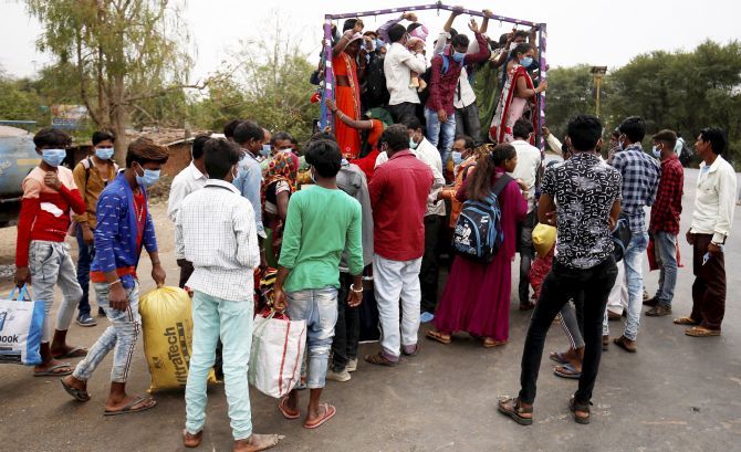 Indians and their families board a truck in Ahmedabad to return to their villages
