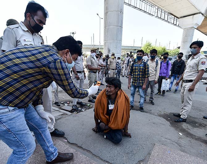 Officials screen an Indian waiting to board a bus to his village at Anand Vihar in New Delhi, March 28, 2020. Photograph: Manvender Vashist/PTI Photo
