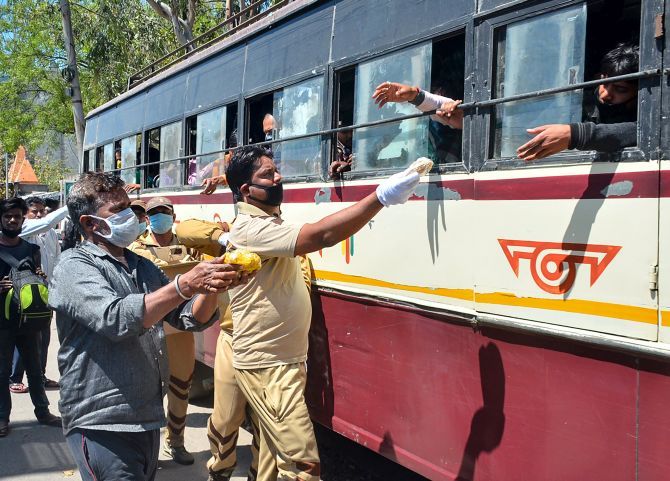 Volunteers provide meals to Indians heading to their villages inside a bus in Moradabad, March 28, 2020. Photograph: PTI Photo