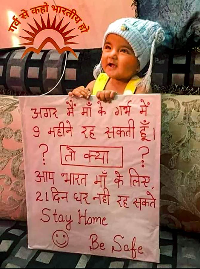 A girl holds a placard on urging people to stay home during a nationwide lockdown in the wake of coronavirus pandemic, in New Delhi.