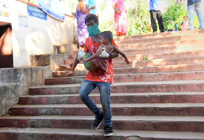 IMAGE: A father rushes to take his child for treatment at King George Hospital after a major chemical gas leakage at LG Polymers industry in RR Venkatapuram village, Visakhapatnam, on Thursday. Photograph: PTI Photo