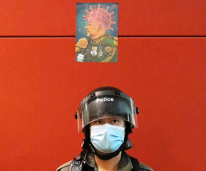A defaced picture mocking Chinese President Xi Jinping and the coronavirus disease is seen above a riot policeman's head in Hong Kong, April 26, 2020. Photograph: Tyrone Siu/Reuters