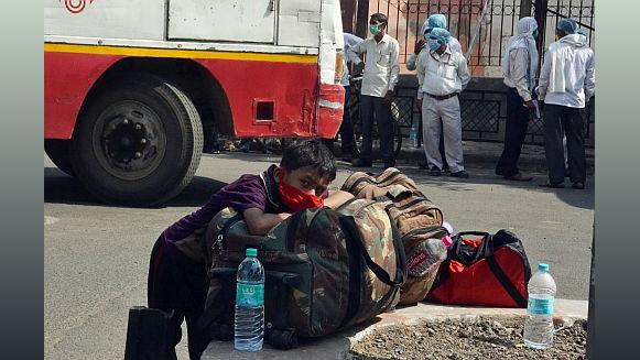 A boy rests on his bags as he waits to board a bus.