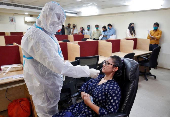 A healthcare worker takes a swab from a woman for a rapid antigen test in Ahmedabad
