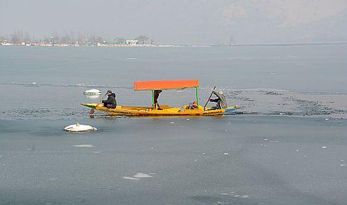 A shikarawala at a partially frozen Dal Lake. Pic: Umar Ganie