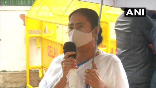 Mamata Banerjee holds her own umbrella while speaking to reporters