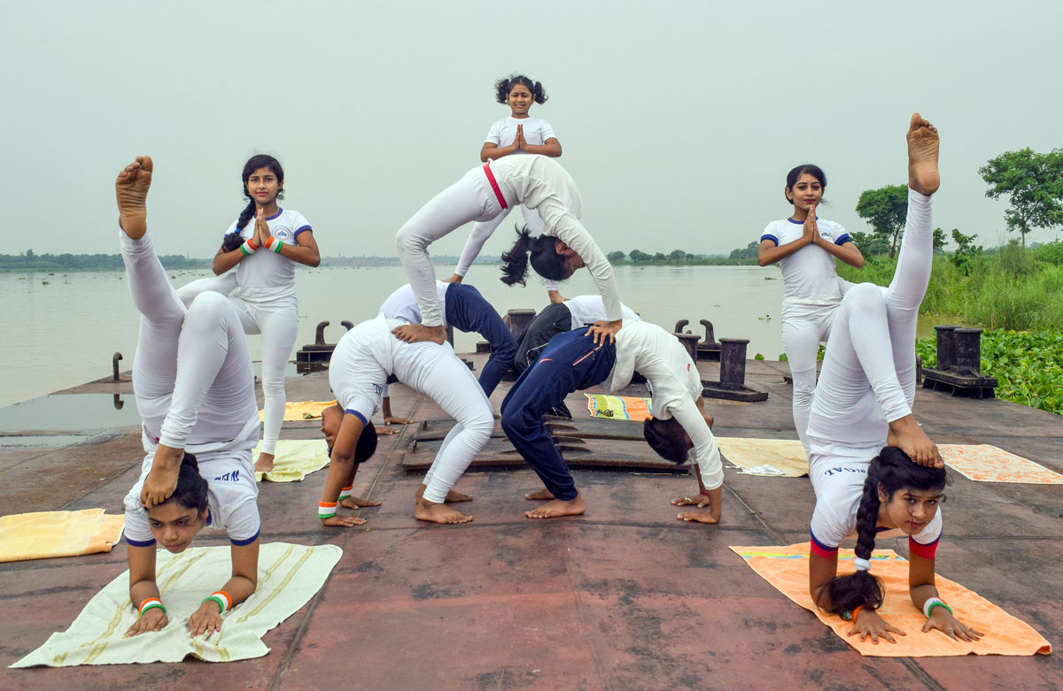 Premium Photo | Young attractive smiling group of acrobats creating pyramid  in hipopening yoga pose practicing acro yoga balancing