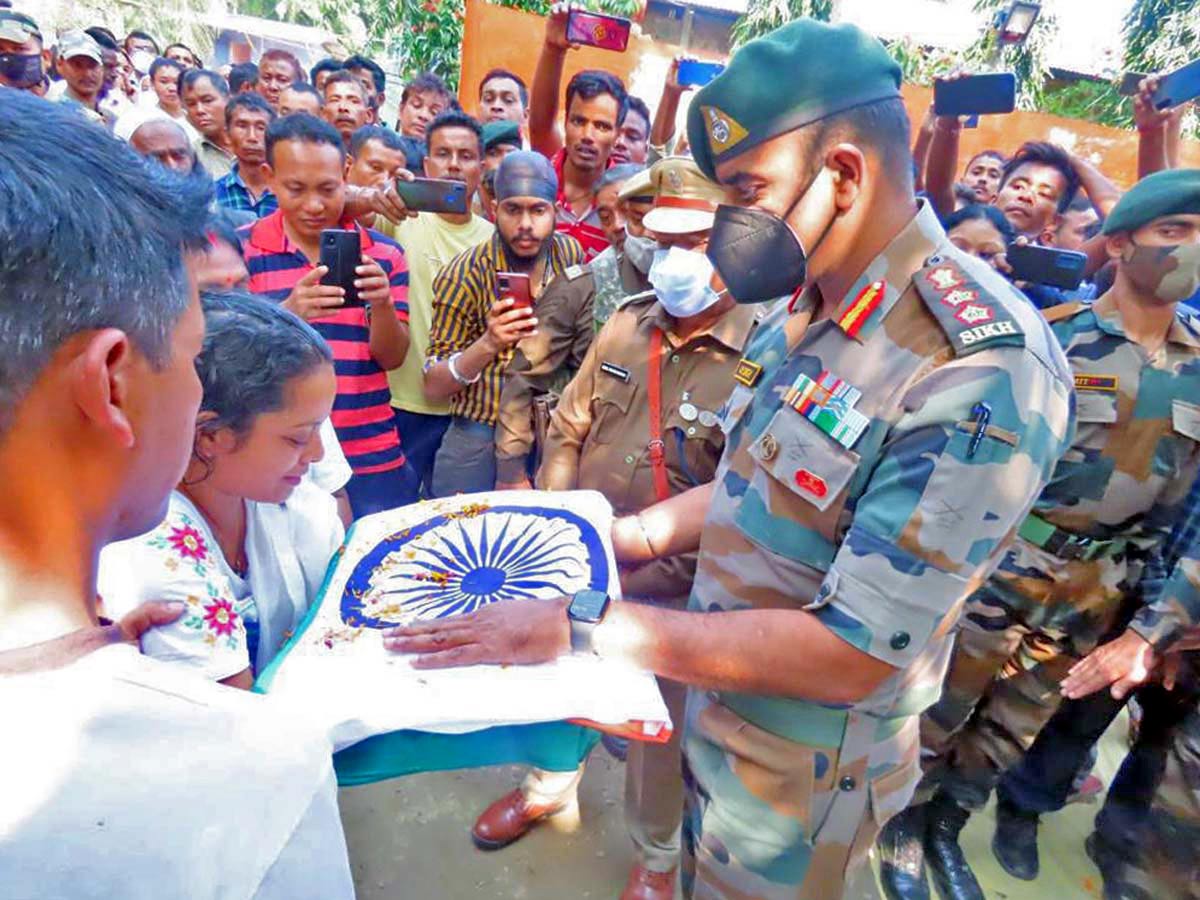 Army personnel hands over the national flag to the Juri Swargiary, wife of Martyr Rifleman Suman Swargiary during the funeral ceremony.