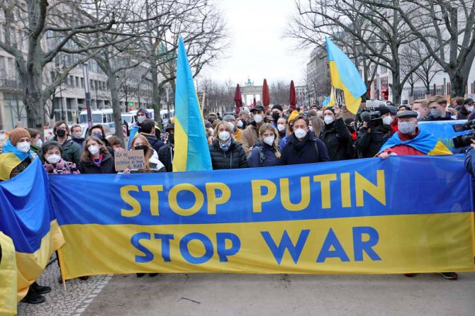 A woman holds a Ukrainian flag next to a banner reading 'Stop Putin' as youth groups protest with a human chain outside the Russian embassy in March 2022
