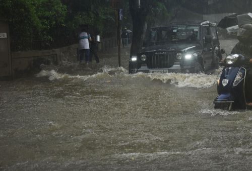 Vehicles ply a waterlogged street in Mumbai
