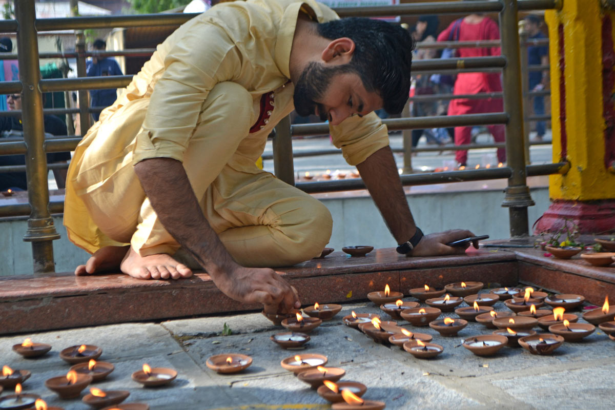 A man lights lamps on the occasion of Kheer Bhavani