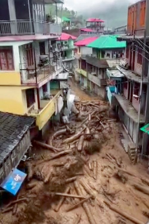 Torrential water flows down a narrow street in Mandi