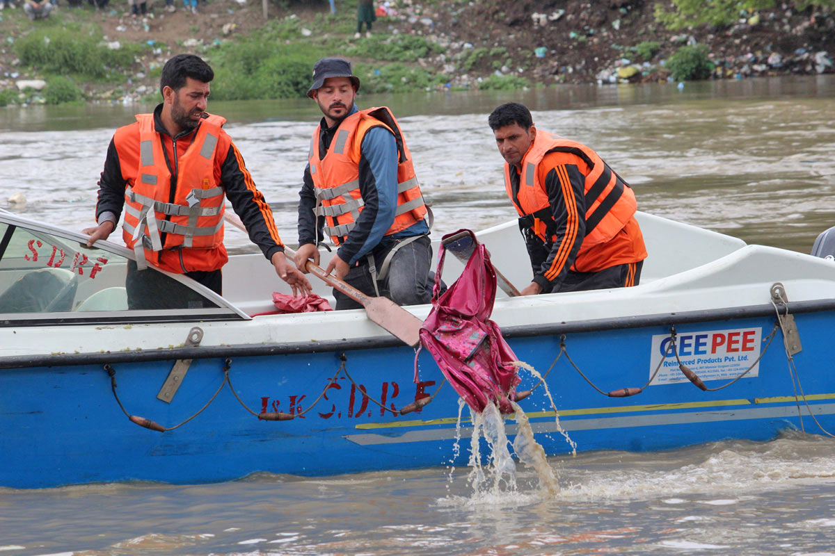 Rescuers fish out a school bag from the river. Pic: Umar Ganie
