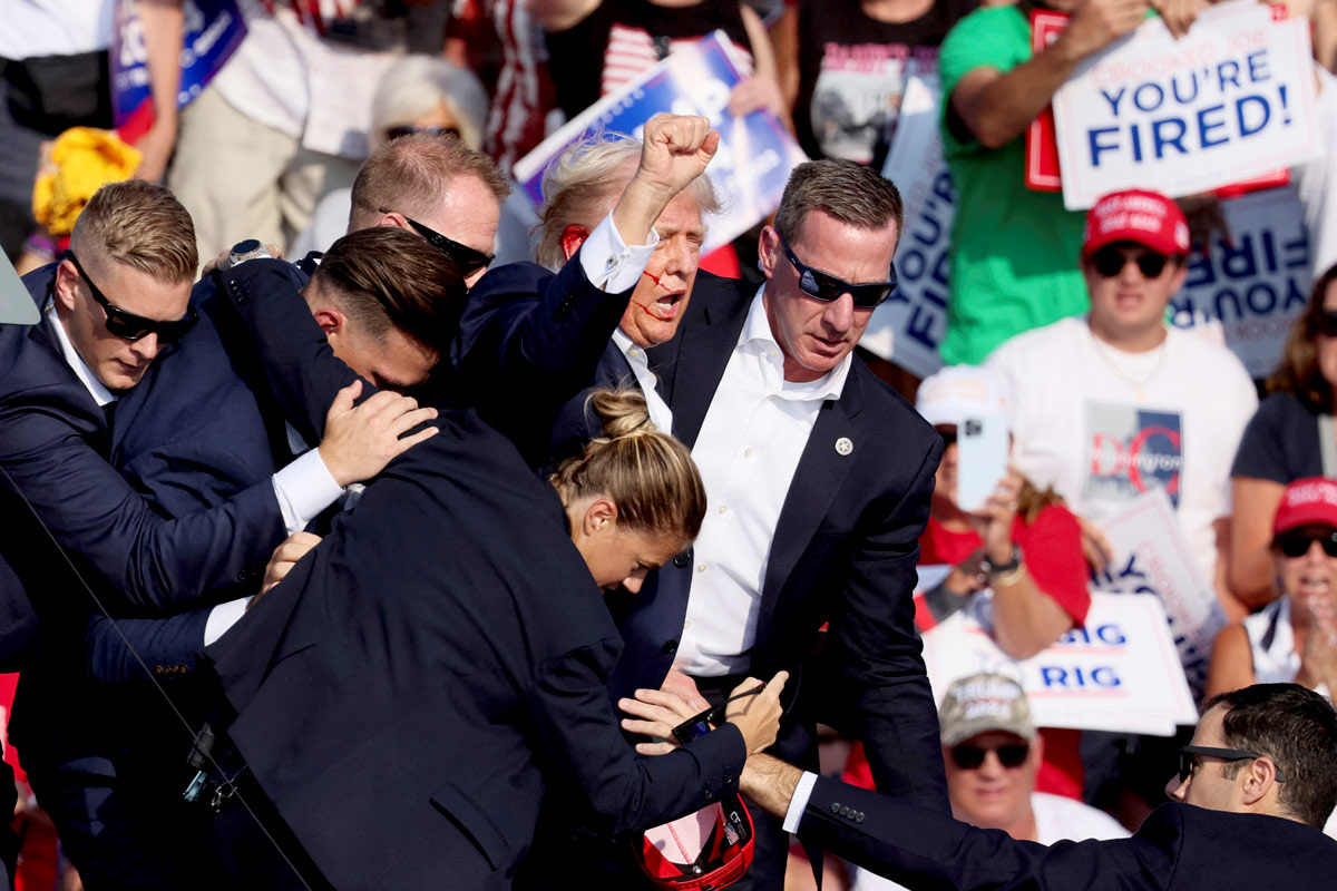 Former US President Donald J Trump is assisted by Secret Service agents after gunfire/Brendan McDermid/Reuters