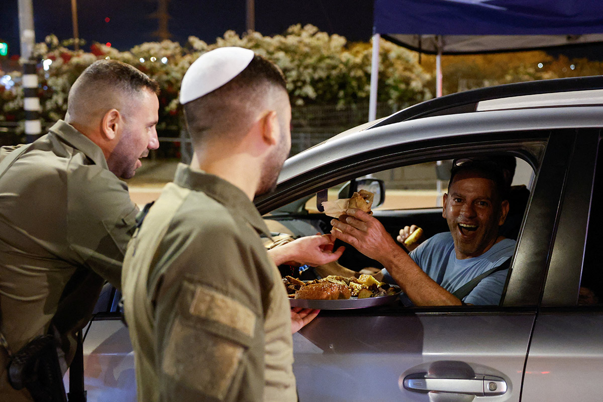 Israeli soldiers give out food to people around