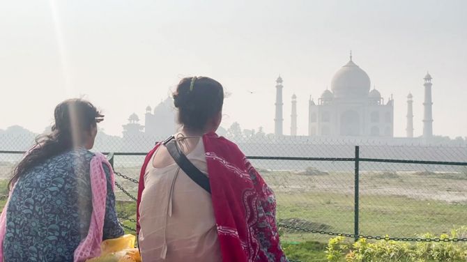 Women watching smog filled view of the Taj Mahal