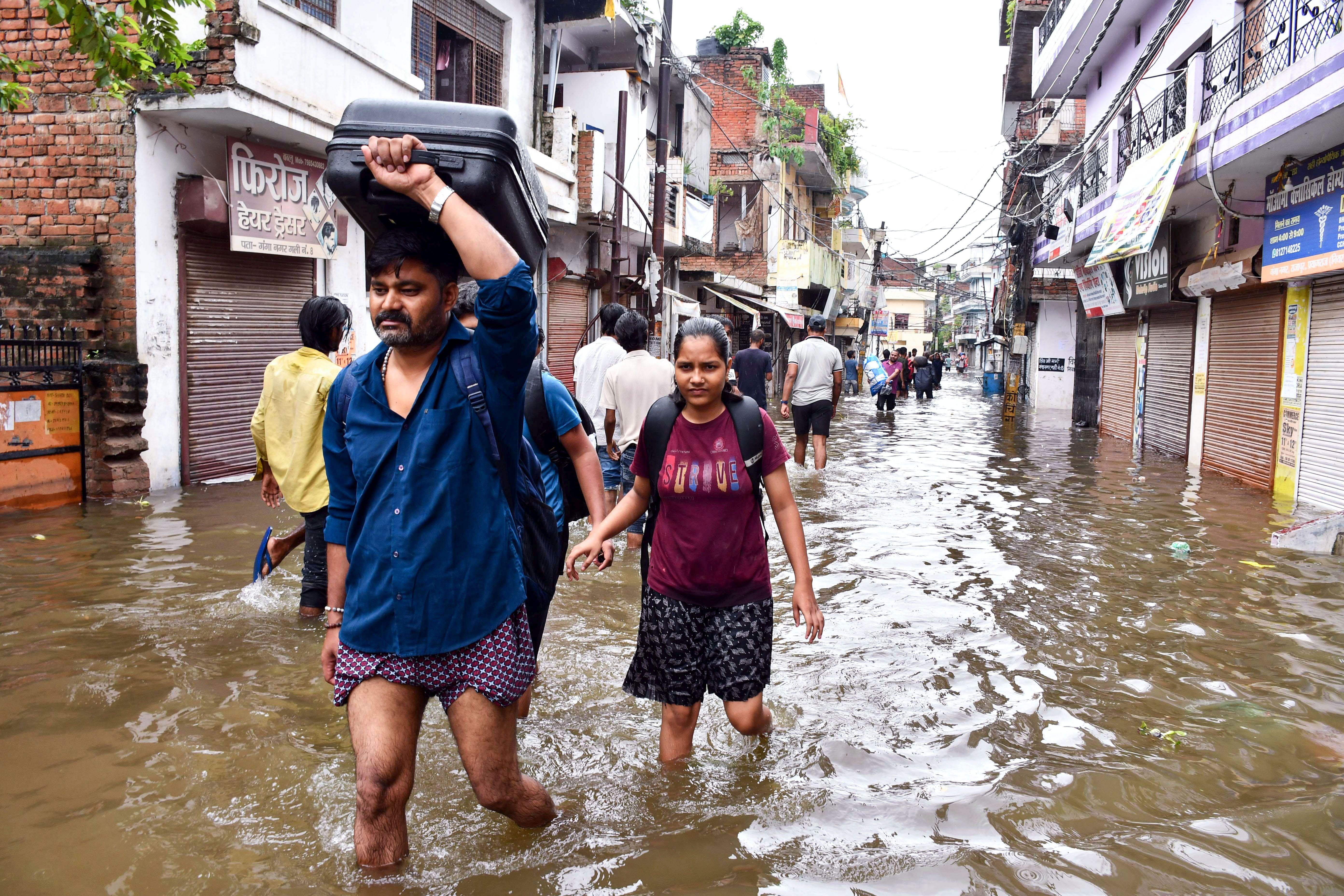 Residents wade through a flooded street in Prayagraj