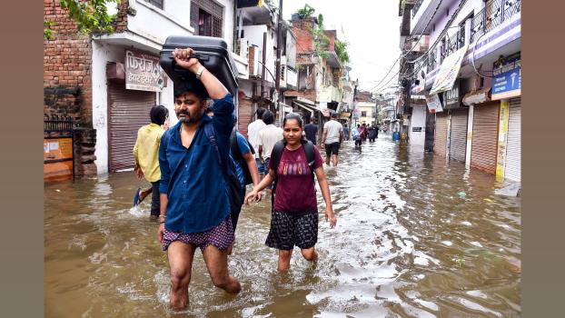 Residents wade through a flooded street in Prayagraj