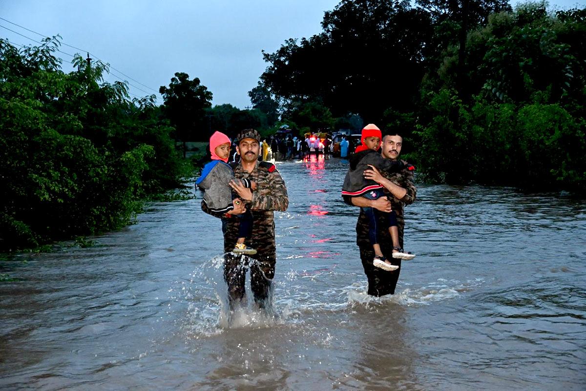 Security personnel carry children through waterlogged Medak areas