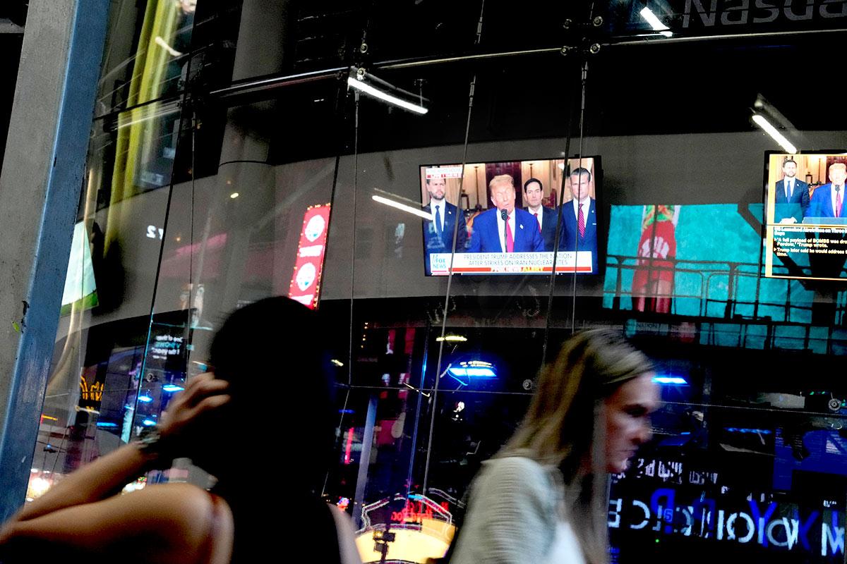 People walk by TVs in US broadcasting Trump's announcement on bombing Iran