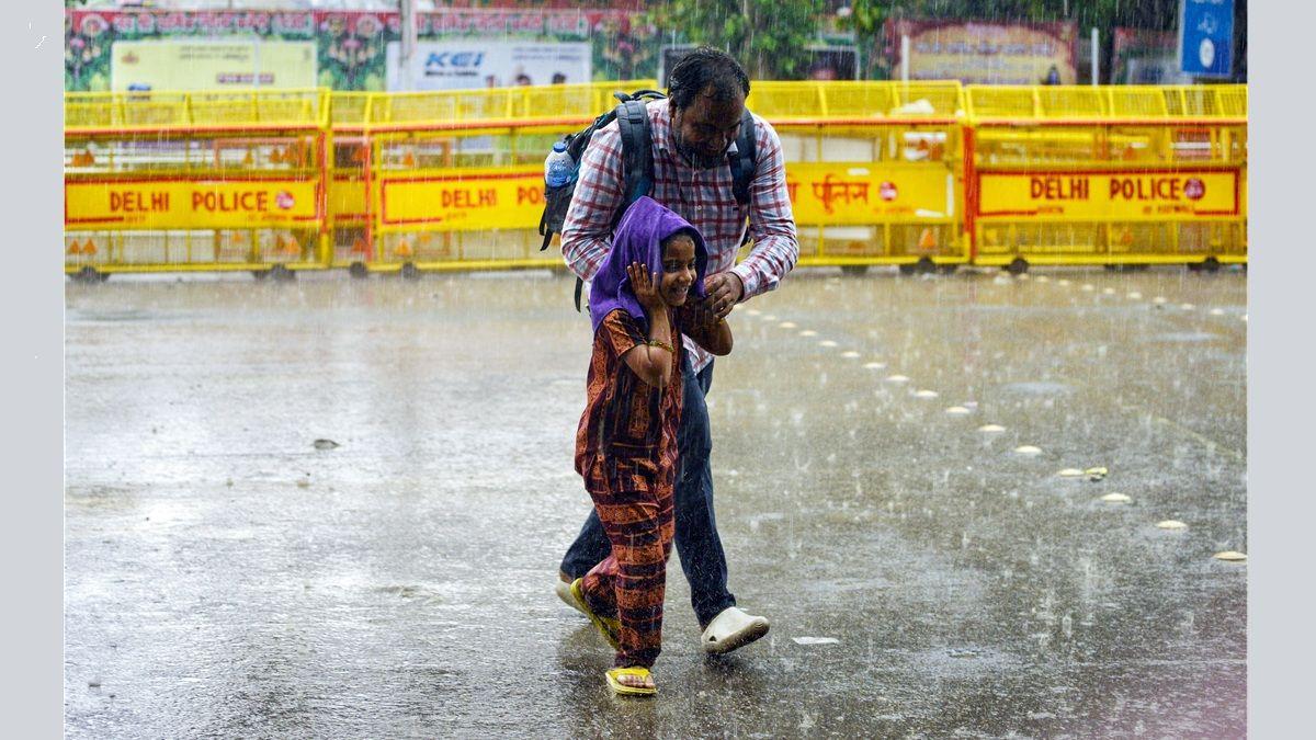 A father and daughter walk through heavy rain, in New Delhi.