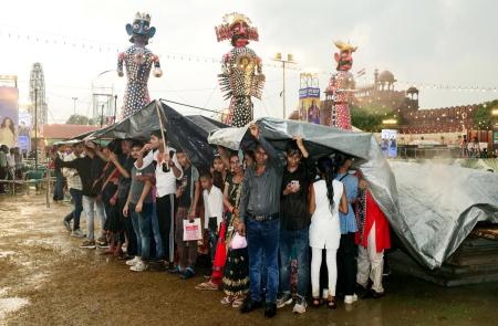 People take shelter under tarpaulins during Ravan Dahan amid heavy rainfall at Nav Dharmik Ramleela People take shelter under tarpaulins during Ravan Dahan amid heavy rainfall at Nav Dharmik Ramleela