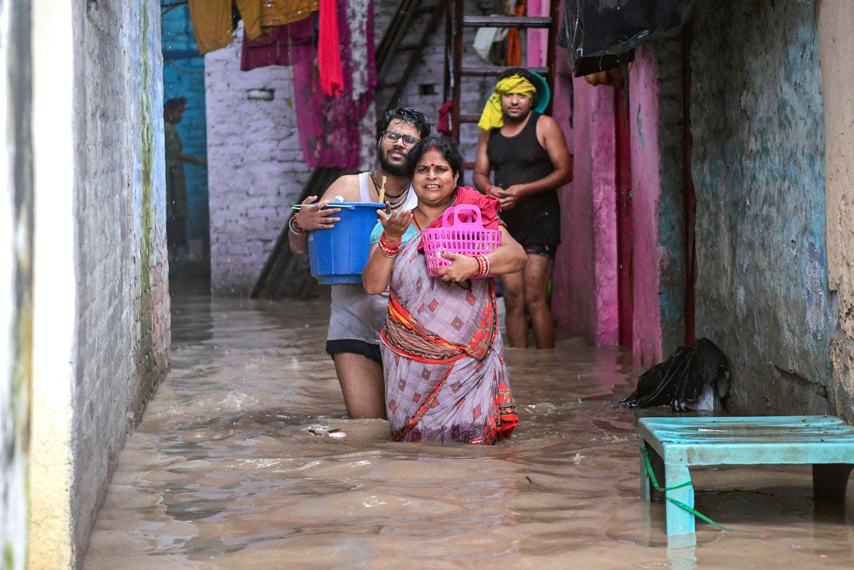 People with their belongings move through a severely waterlogged area as the river Yamuna crosses the danger mark following incessant rainfall, at Yamuna Bazar in New Delhi