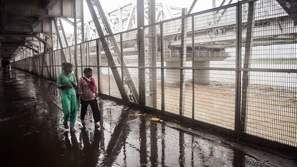 People cross the Loha Pul as the river Yamuna crosses the danger mark following incessant rainfall, in New Delhi