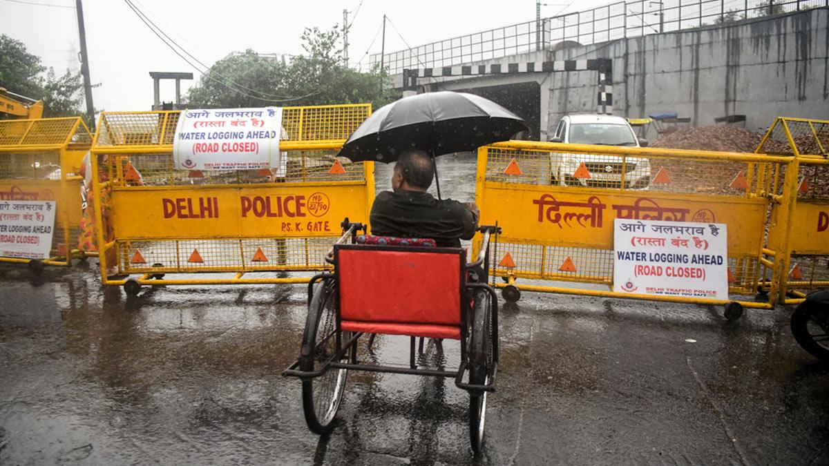 A specially abled man stands near the barricades installed to close the entry to the Loha Pul as the river Yamuna crosses the danger mark following incessant rainfall, in New Delhi