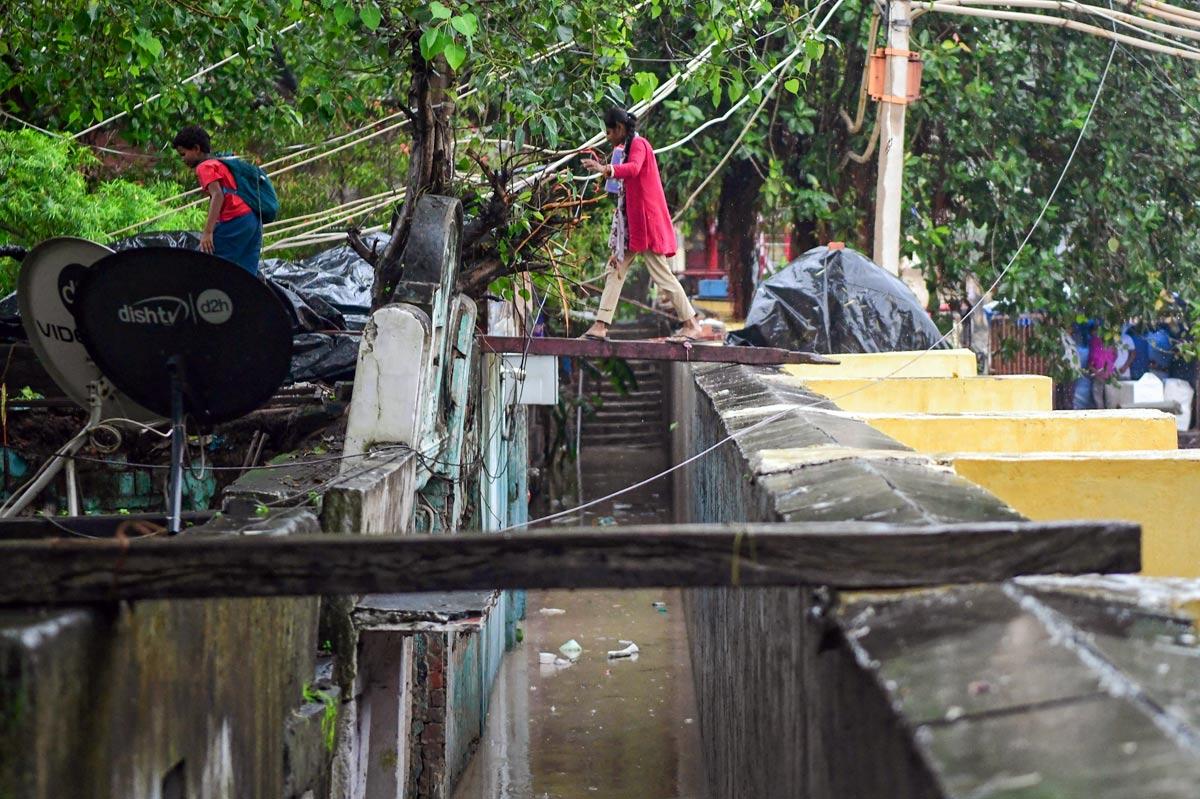 A girl crosses a waterlogged area using a wooden plank as the river Yamuna crosses the danger mark following incessant rainfall, at Yamuna Bazar in New Delhi