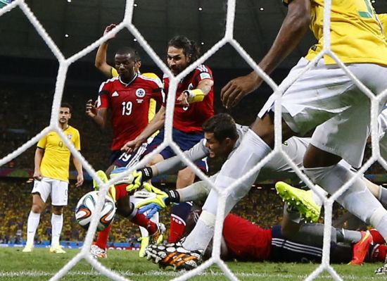 Brazil goalkeeper Julio Cesar tries to stop an an attempt at goal by Colombia's Mario Yepes (No 3)