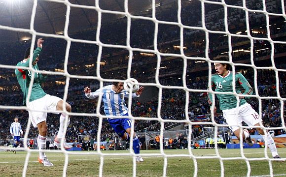 Argentina's Carlos Tevez (centre) scores a goal past Mexico's Efrain Juarez (right) and Francisco Rodriguez 