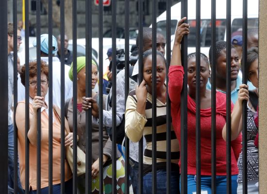 Bystanders look through a fence hoping to catch a sight of Olympic and Paralympic track star Oscar Pistorius 