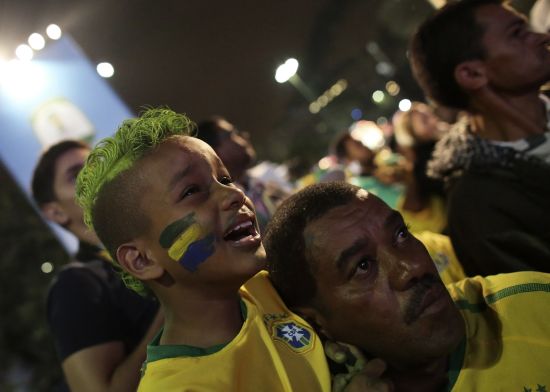 A Brazilian boy fan cries next to his father 