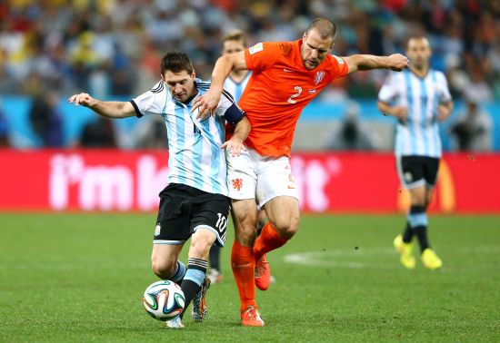 Lionel Messi of Argentina is challenged by Ron Vlaar of the Netherlands